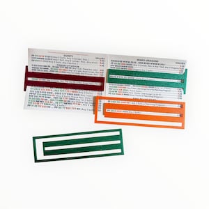 May include: A collection of colorful game cards with text and numbers. The cards are in shades of red, green, and orange, with white text. The cards appear to be for a board game or card game.