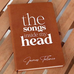 Könnte beinhalten: Ein braunes, ledergebundenes Tagebuch mit dem Text "the songs inside my head" und dem Namen "James Talince" in weißer Schrift.