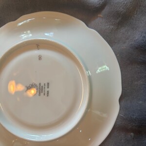 Könnte beinhalten: Ein weißer Porzellanteller mit gewelltem Rand. Die Unterseite des Tellers trägt den Text "Castleton China York Rose". Der Teller hat eine glänzende Oberfläche und ein schlichtes, elegantes Design, das sich zum Servieren von Speisen eignet.