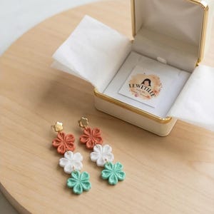 May include: A set of three ceramic mugs with a speckled, matte finish. The mugs are in shades of cream, light gray, and dark gray. Each mug has a simple, minimalist design and a rounded handle.