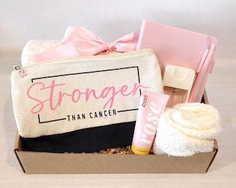 May include: A gift basket containing a canvas cosmetic bag with the words "Stronger Than Cancer" in pink, a pink bow, a pink notebook, a pen, a bottle of perfume, a tube of rose-scented lotion, and a fluffy white face pad.