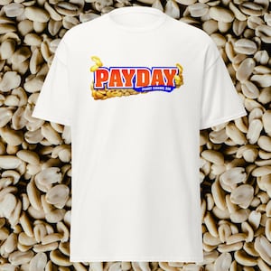May include: White t-shirt with a graphic of the Payday candy bar logo. The logo is in red, blue, and orange with the text "PAYDAY PEANUT CARAMEL BAR".