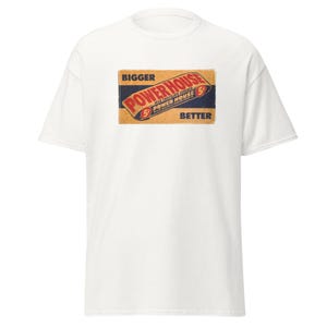 Puede incluir: Camiseta blanca con un gráfico de estilo vintage de una barra de chocolate etiquetada como "Powerhouse" con el texto "Bigger" y "Better" en la caja.
