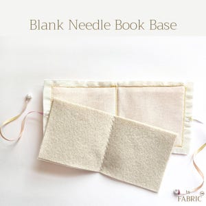 May include: A blank needle book base featuring a rectangular off-white fabric cover with gold stitched edges and an interior page of beige felt. The item includes thin ribbons with small beads at the ends and the text Blank Needle Book Base.