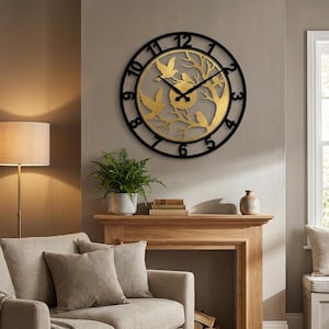Puede incluir: Un reloj de pared decorativo negro y dorado con un diseño de pájaros y árboles. El reloj tiene forma circular con números y manecillas negros. El círculo interior tiene un acabado dorado con pájaros y ramas.
