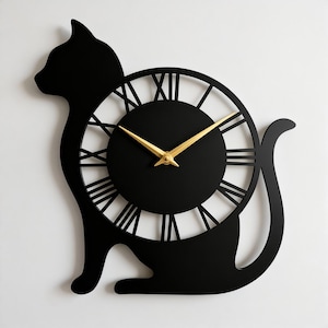 Peut inclure: Horloge murale noire en forme de chat avec un cadran circulaire. L'horloge présente des aiguilles dorées et des chiffres romains. La silhouette du chat est noire, créant un contraste saisissant.