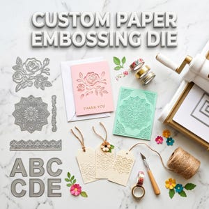 Op de afbeelding: Aangepaste papier embossing stansvormenset met diverse ontwerpen, waaronder bloemen- en geometrische patronen. Bevat letterstansvormen, een roze kaart met een rozenontwerp en een groene kaart met een mandala-ontwerp. De tekst "THANK YOU" is zichtbaar op de roze kaart.