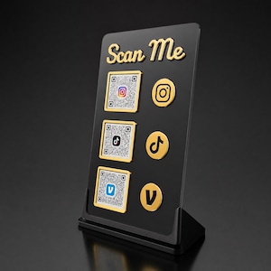Puede incluir: Un letrero rectangular negro de acrílico con soporte dorado que presenta el texto Scan Me en letra dorada. Muestra tres códigos QR cuadrados con bordes dorados y tres iconos circulares dorados de redes sociales para Instagram, TikTok y Venmo.