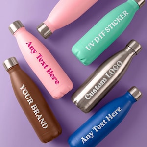 May include: A selection of insulated water bottles in shades of pink, teal, brown, silver, and blue. Each bottle has a silver cap and is printed with custom text like "Any Text Here", "Your Brand", and "Custom Logo".