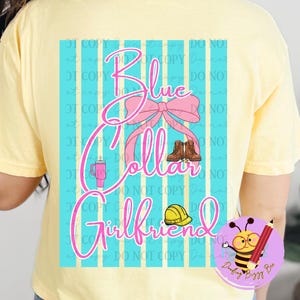 May include: A light yellow t-shirt with a graphic on the back. The graphic features the words "Blue Collar Girlfriend" in pink script, with a pink bow, boots, a tumbler, and a hard hat. The background has blue stripes.