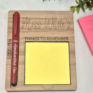 May include: Wooden desk organiser with the text "Miss White's THINGS TO REMEMBER". Includes a yellow sticky note pad and a red pen with the text "GOOD PEN Handwriting Pen".