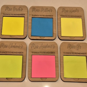 May include: Six wooden Things to Remember memo holders with colorful sticky notes. Each holder is engraved with a name and the words "THINGS TO REMEMBER". The sticky notes are yellow, blue, pink, and green.
