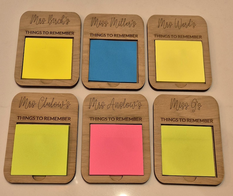 May include: Six wooden Things to Remember memo holders with colorful sticky notes. Each holder is engraved with a name and the words "THINGS TO REMEMBER". The sticky notes are yellow, blue, pink, and green.