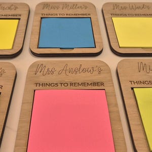May include: Six wooden memo holders with colorful sticky notes. Each holder has a name engraved at the top and the words "THINGS TO REMEMBER" below. The sticky notes are yellow, blue, and pink.