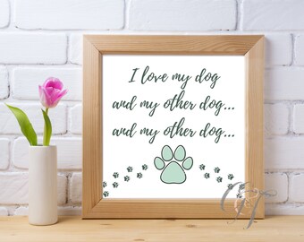 May include: A framed print with a white background and green text that reads "I love my dog and my other dog... and my other dog..." with a green paw print and smaller paw prints at the bottom.