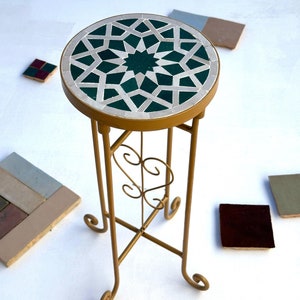 Peut inclure: Un support en métal doré avec un plateau rond en mosaïque de carreaux verts et blancs. Le support a un design décoratif enroulé sur les pieds.