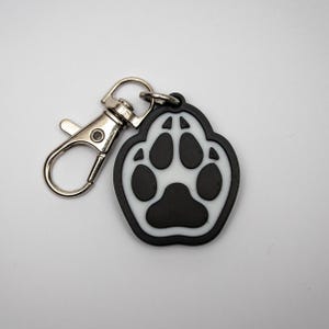 May include: A black and white paw print keychain with a silver metal clasp.