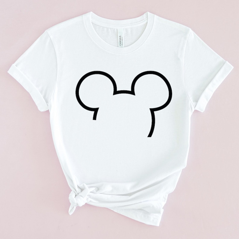 Puede incluir: Camiseta blanca con un contorno negro de las orejas de Mickey Mouse.