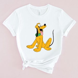 May include: White t-shirt with a cartoon image of Pluto, a yellow dog with a green collar, sitting and looking to the right.