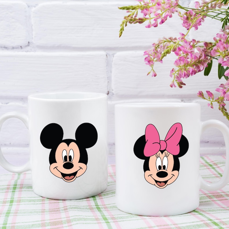 Peut inclure: Deux tasses en c&eacute;ramique blanche avec des images de dessins anim&eacute;s de Mickey Mouse et Minnie Mouse. Mickey Mouse porte un short rouge et des chaussures jaunes. Minnie Mouse porte un n&oelig;ud rose et des chaussures rouges.