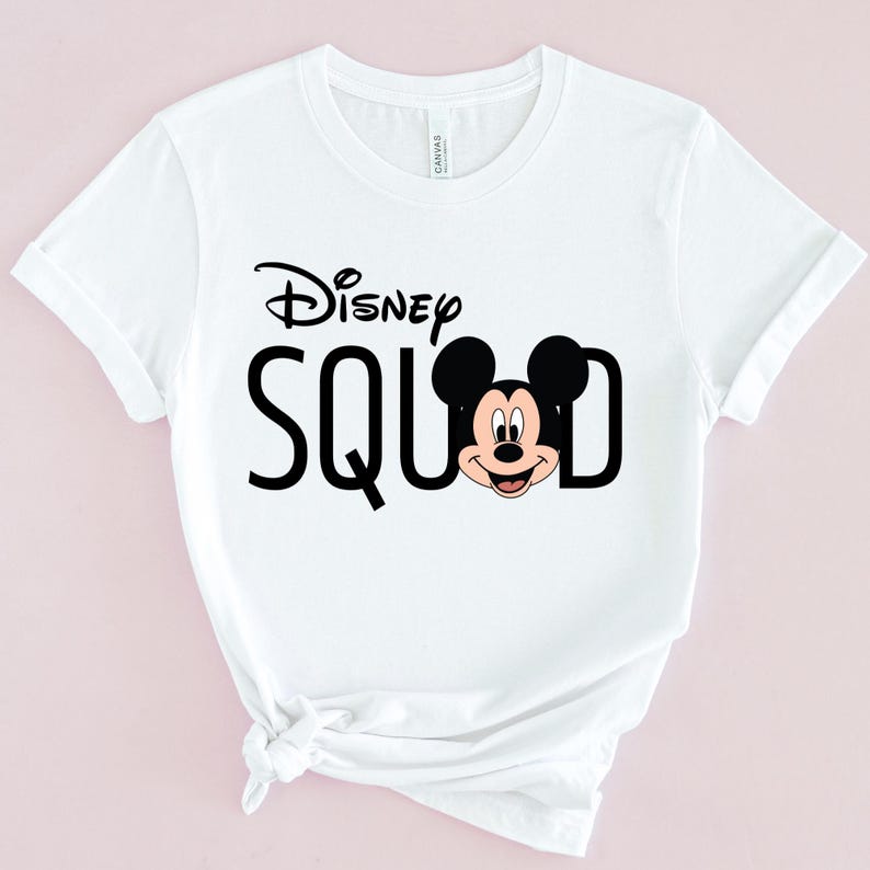 Puede incluir: Camiseta blanca con la frase "Disney Squad" en negro, con la cara de Mickey Mouse integrada en la "D". La camiseta tiene mangas cortas y cuello redondo, perfecta para uso casual.