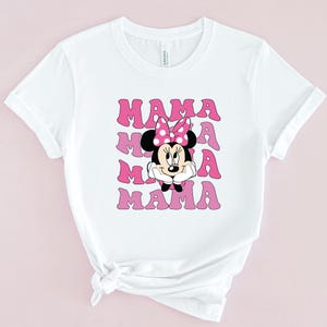 May include: White t-shirt with a pink and white graphic of Minnie Mouse and the word "MAMA" repeated four times.