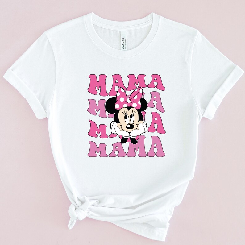 May include: White t-shirt with a pink and white graphic of Minnie Mouse and the word "MAMA" repeated four times.