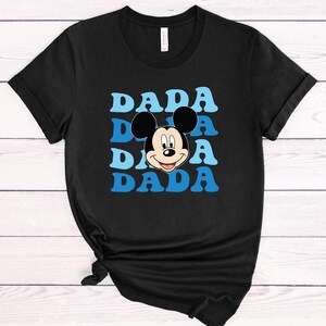 May include: Black t-shirt with a blue and white graphic of Mickey Mouse's face and the word "DADA" repeated four times.