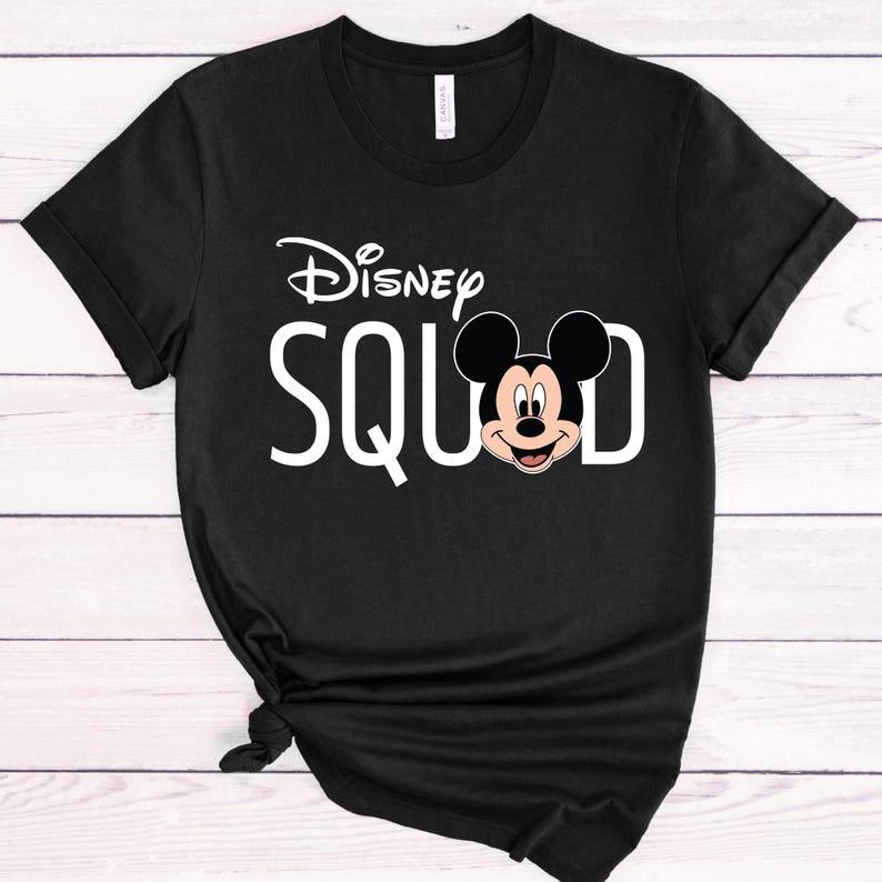 Puede incluir: Camiseta negra con la frase blanca "Disney SQUAD", el logo de Disney y un gr&aacute;fico de Mickey Mouse. La camiseta tiene mangas cortas y cuello redondo.