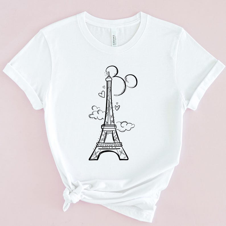 May include: White t-shirt featuring a black and white illustration of the Eiffel Tower with Mickey Mouse ears and hearts.