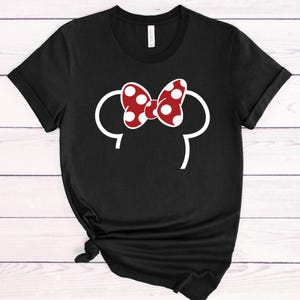 Op de afbeelding: Zwart T-shirt met een witte omtrek van muizenoren en een rode strik met witte stippen. Het shirt is een casual stijl, geschikt voor dagelijks gebruik. Het ontwerp is een speels en herkenbaar stripfiguur.