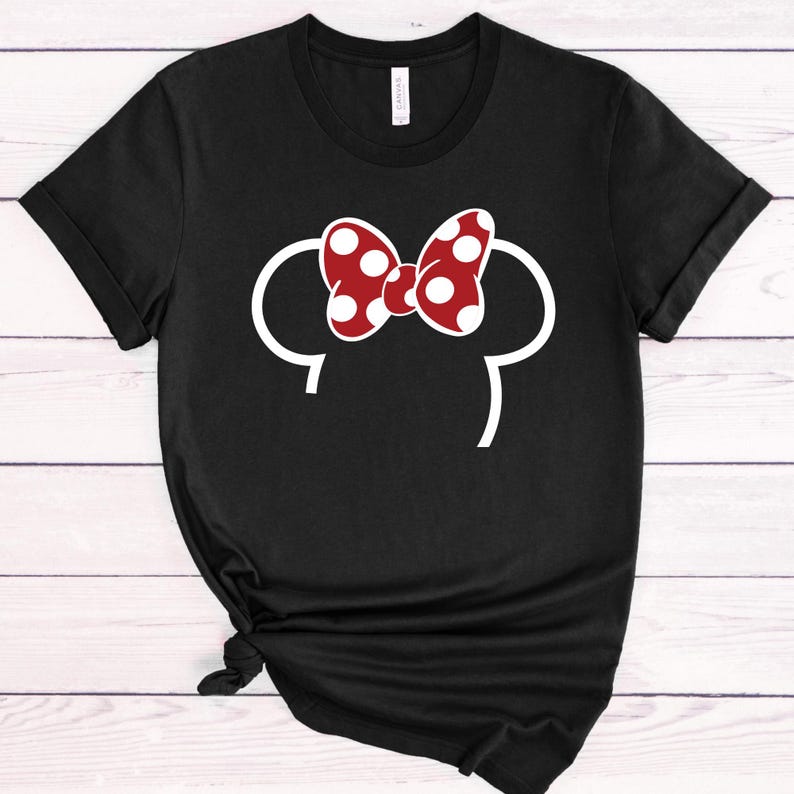 Op de afbeelding: Zwart T-shirt met een witte omtrek van muizenoren en een rode strik met witte stippen. Het shirt is een casual stijl, geschikt voor dagelijks gebruik. Het ontwerp is een speels en herkenbaar stripfiguur.