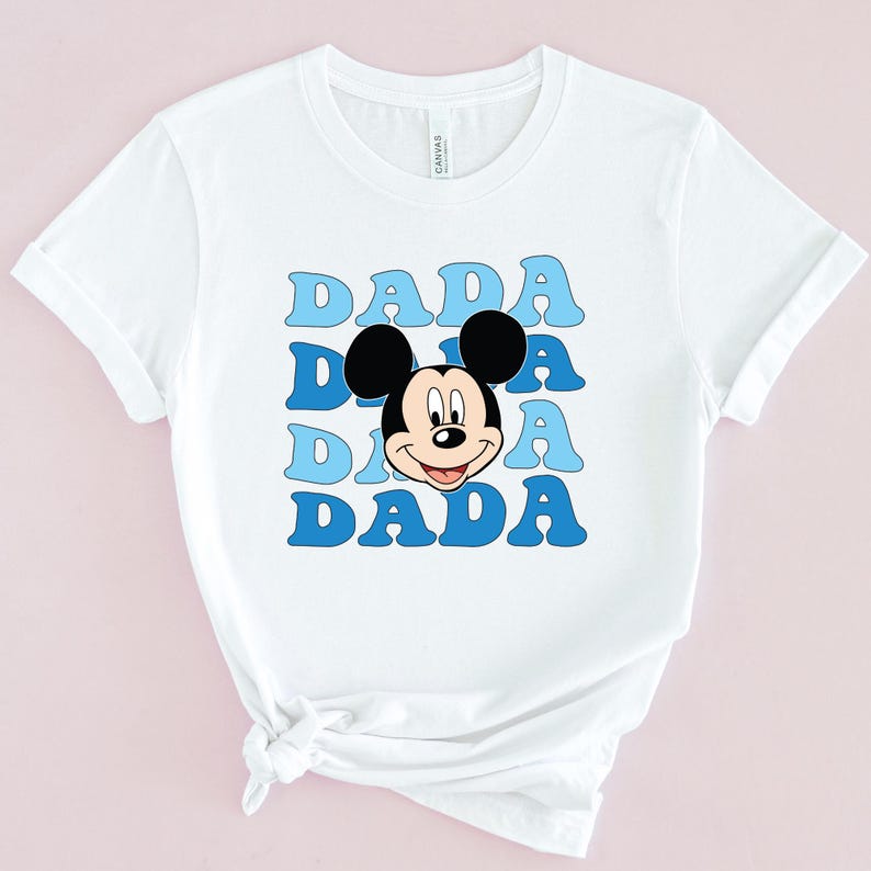 May include: White t-shirt with a blue and light blue graphic of Mickey Mouse's head and the word "DADA" repeated four times.