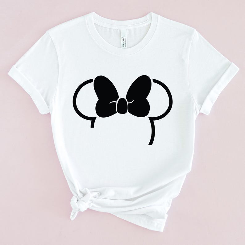 Puede incluir: Camiseta blanca con una silueta negra de las orejas y el lazo de Minnie Mouse.