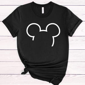 Op de afbeelding: Zwart T-shirt met een witte omtrek van een muizenkop. Het shirt heeft korte mouwen en een ronde hals. De onderkant van het shirt is geknoopt. Het shirt is gemaakt van een zacht materiaal.