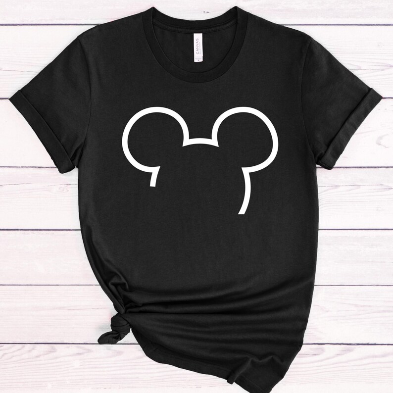 Op de afbeelding: Zwart T-shirt met een witte omtrek van een muizenkop. Het shirt heeft korte mouwen en een ronde hals. De onderkant van het shirt is geknoopt. Het shirt is gemaakt van een zacht materiaal.