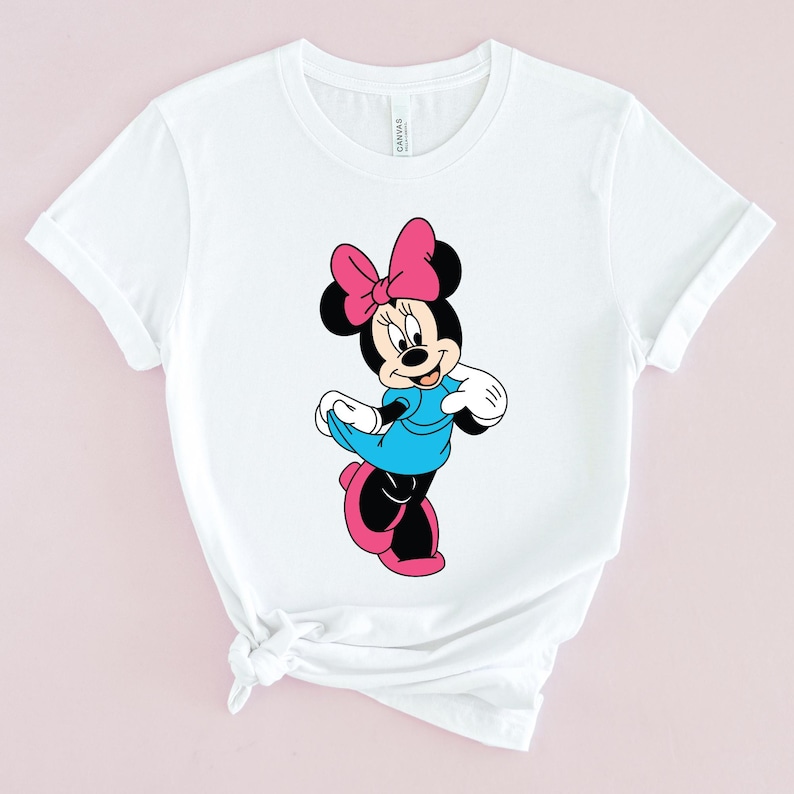 May include: White t-shirt with a cartoon image of Minnie Mouse wearing a blue dress and a pink bow.