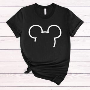 Puede incluir: Camiseta negra con un contorno blanco de las orejas de Mickey Mouse.