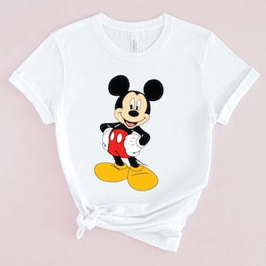 May include: White t-shirt with a cartoon image of Mickey Mouse in a red and yellow outfit.
