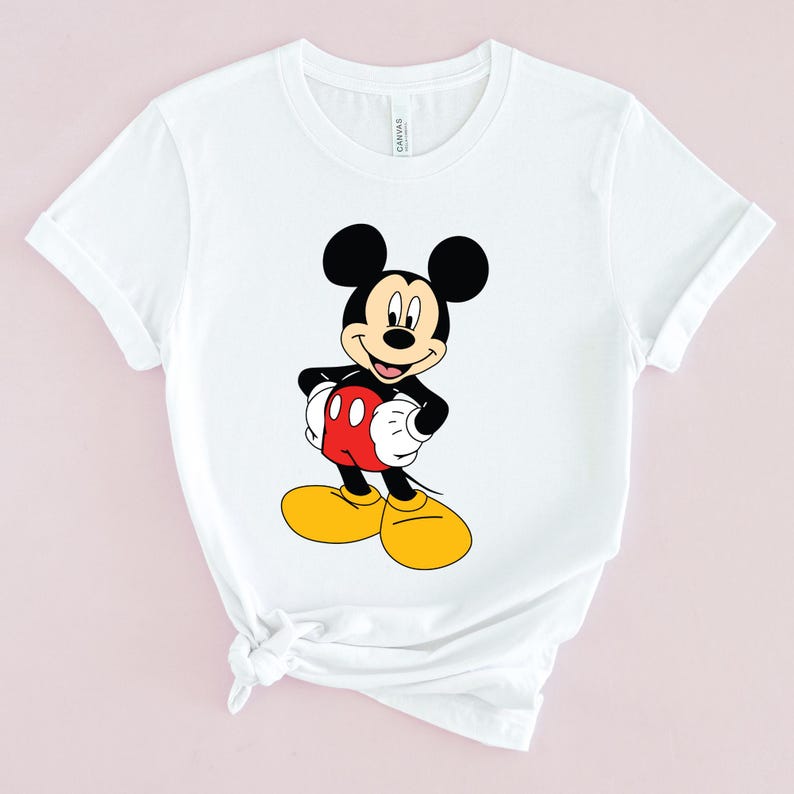 May include: White t-shirt with a cartoon image of Mickey Mouse in a red and yellow outfit.
