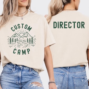 Custom Camp Shirt With Mountain Landscape And River Design On Front And Camper Text On Back, Personalized Camping T Shirt For Family And Group Trips, Ideal Outdoor Adventure Shirt For Hiking And Nature Activities.