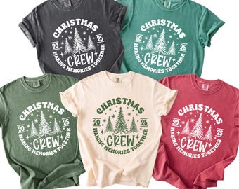 May include: A collection of five crew neck t-shirts in various colors: charcoal, teal, olive green, cream, and burgundy. Each shirt features a circular graphic with the word "CHRISTMAS", the year "2025", and the text "MAKING MEMORIES TOGETHER CREW".