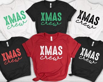 May include: A collection of short-sleeved t-shirts in various colors, including white, black, and red. Each shirt features the text "XMAS crew" in a contrasting color. The shirts are likely for a Christmas-themed event.
