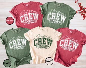 Może przedstawiać: Kilka koszulek z krótkim rękawem w odcieniach czerwieni, zieleni i kremu. Każda koszulka zawiera napis "Christmas CREW MAKING MEMORIES TOGETHER" w pogrubionej czcionce. Koszulki mają luźny krój.