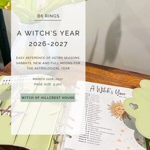Puede incluir: Un archivador de anillas B6 verde claro abierto en una página titulada "A Witch's Year 2026-2027". El tamaño de la página es de 13,46x17,78 cm. El archivador está sobre una superficie de madera, con el texto "Referencia fácil de las estaciones astro, sabbats, lunas nuevas y llenas para el año astrológico."