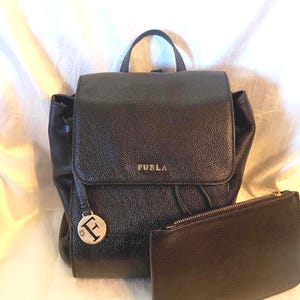 Furla zwarte leren rugzak met kiezelstenen suède klepsluiting met trekkoord dubbele bandjes aan de achterkant zwart leren zakje met rits aan de bovenkant Italiaans leer