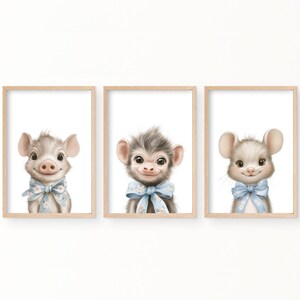 Puede incluir: Tres impresiones de arte de guardería imprimibles con un cerdo, un mono y un ratón. Cada animal lleva un lazo azul con detalles florales blancos. Las impresiones están sobre un fondo blanco.
