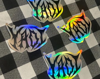 Può includere: Quattro adesivi olografici con un design nero e argento su uno sfondo a scacchi bianco e nero. Ogni adesivo ha la parola "FAIR" in un carattere stilizzato. Gli adesivi hanno una lucentezza arcobaleno.