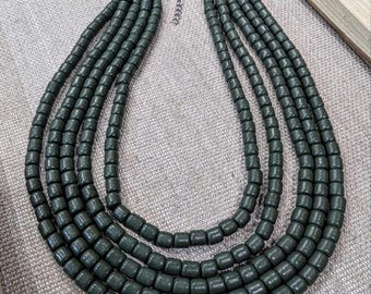 May include: A multi-strand necklace featuring five rows of dark forest green cylindrical beads. The necklace is connected by a silver-toned metal clasp and includes an adjustable silver-toned chain extender at the back for length customisation.