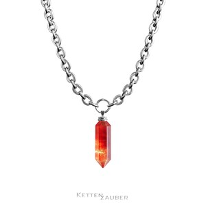 May include: A silver chain necklace with a red crystal pendant in the shape of a long, pointed, geometric shape.